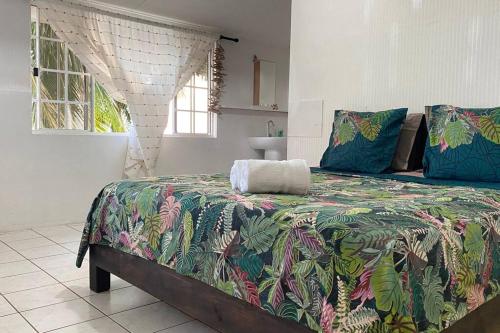 1 dormitorio con 1 cama con un edredón colorido en Bienvenue chez Fare Na’i en Fare