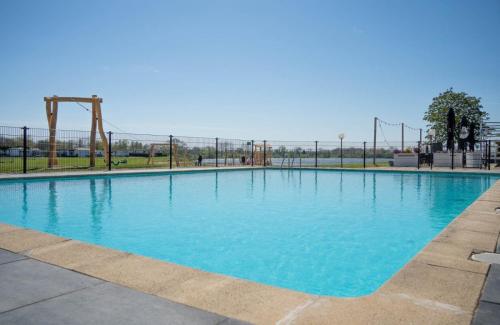 a large swimming pool with an empty playground at Luxe chalet in prachtig natuurgebied in Lith