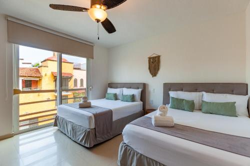 a bedroom with two beds and a large window at Via Tendenza Condos in Playa del Carmen