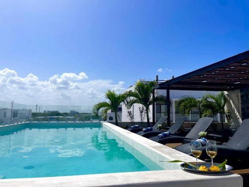 a swimming pool with chairs and a table with wine glasses at Suite de lujo 1 Hab. Depto 203 in Playa del Carmen