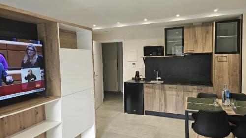 a living room with a flat screen tv and a kitchen at Apartamentos O Caneiro in Portomarin