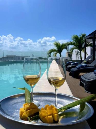 two glasses of wine on a tray next to a pool at Suite de lujo 1 Hab. Depto 203 in Playa del Carmen