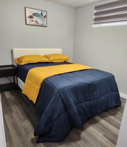 1 cama con edredón azul y amarillo en una habitación en Entire Basement Suite with Private Entrance, en Winnipeg