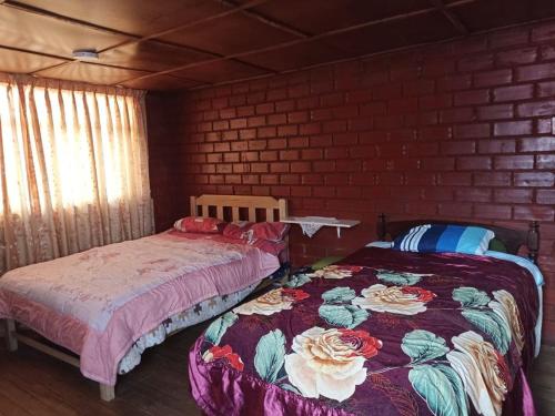 1 Schlafzimmer mit 2 Betten und Ziegelwand in der Unterkunft DEPA WANKA in Huancayo