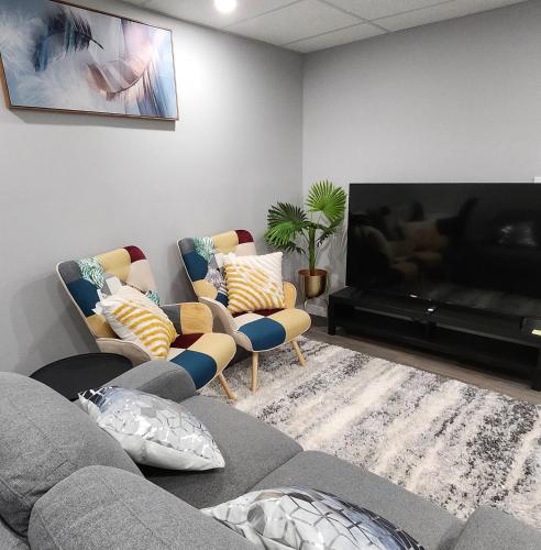 Una sala de estar con un sofá y un televisor de pantalla plana. en Entire Basement Suite with Private Entrance, en Winnipeg