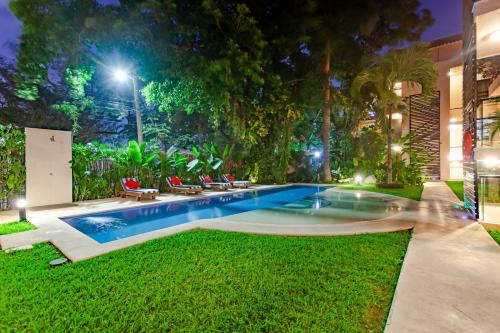 a swimming pool in the yard of a house at night at Via Tendenza Condos in Playa del Carmen