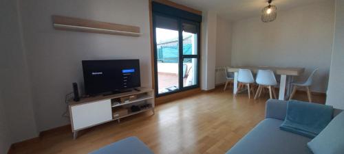sala de estar con sofá, TV y mesa en Apartamento con 2 dormitorios, garaje y terraza junto a Valladolid en Valladolid