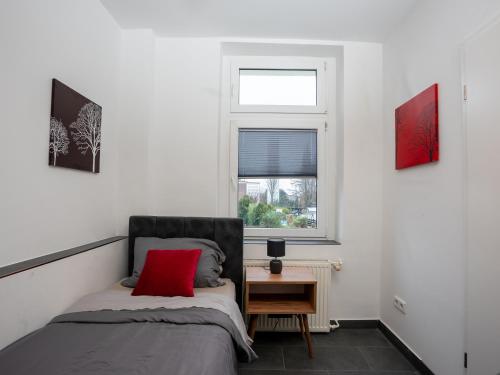 una camera da letto con un letto con un cuscino rosso e una finestra di SR24 - Stillvolles gemütliches Apartment 2 in Oer-Erkenschwick a Oer-Erkenschwick