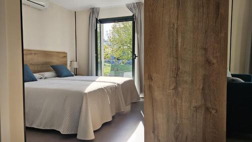 a bedroom with a bed and a large window at Apartamentos O Caneiro in Portomarin