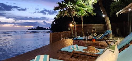 een resort met een tafel en stoelen naast het water bij Villa Moana in Atiha
