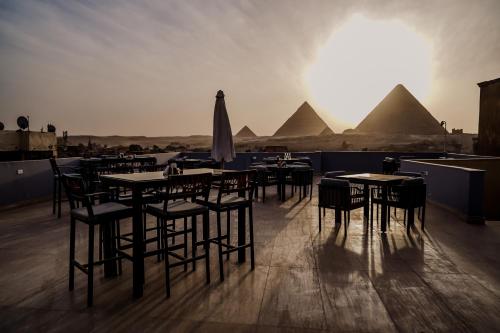 a group of tables and chairs with pyramids in the background at Pyramids Inn in Cairo
