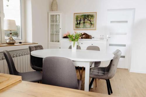 uma sala de jantar branca com uma mesa e cadeiras brancas em Las i Rzeka em Wyszków