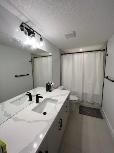 a white bathroom with a sink and a toilet at NEW Modern and Bright Suite near WEM in Edmonton