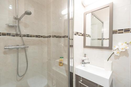 y baño con ducha, lavabo y espejo. en Appartements Massena en Niza