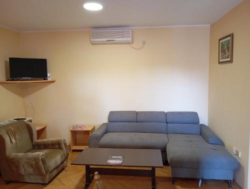 sala de estar con sofá azul y silla en Apartman Sekulić, en Sombor