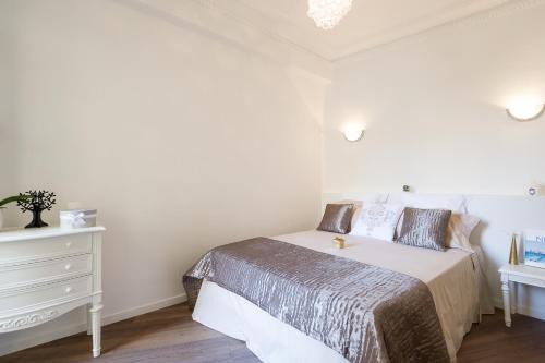 a white bedroom with a bed and a dresser at Appartements Massena in Nice