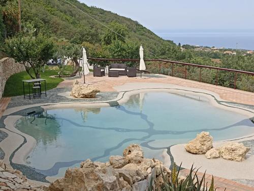 a swimming pool with blue water and rocks at Il Corbezzolo Tropea Residence in Tropea