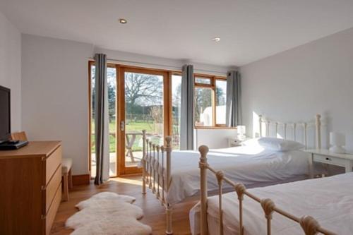 a bedroom with two beds and a large window at Bramble, luxury in idyllic setting, at Hollambys in Groombridge