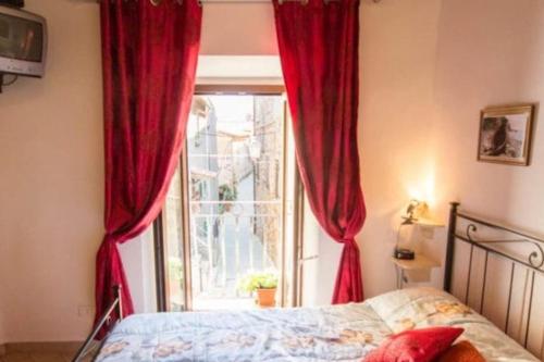 een slaapkamer met een bed en een raam met rode gordijnen bij Casa Il girasole in Boccheggiano