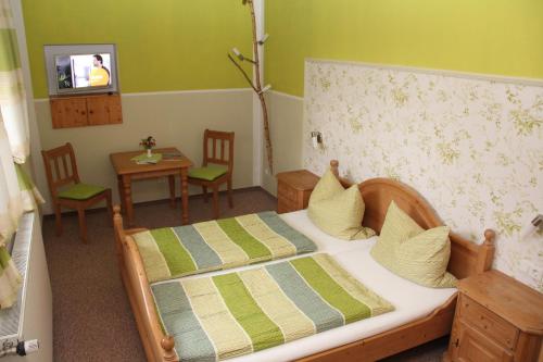 a bedroom with a bed and a table and a television at Pension Zumpe in Stolpen