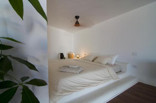 a white bed in a white room with a plant at La Terraza! Studio Apartment in Puerto de la Cruz