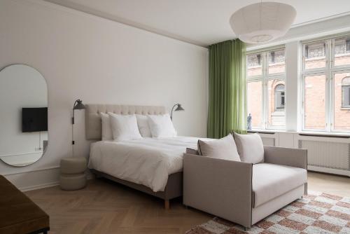 a white bedroom with a bed and a chair at Latin Quarter by Daniel&Jacob's in Copenhagen