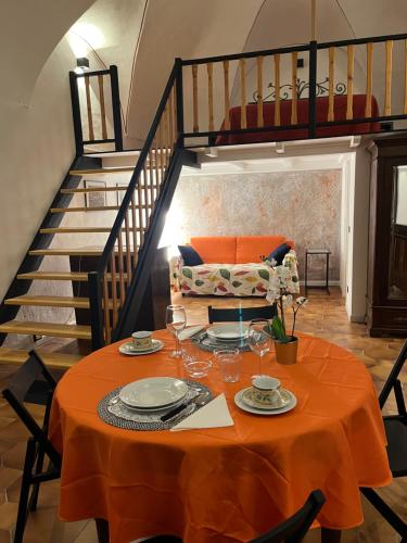 uma mesa com uma toalha de mesa laranja e uma escada em Il Loft In Piazza 2 em Dolceacqua