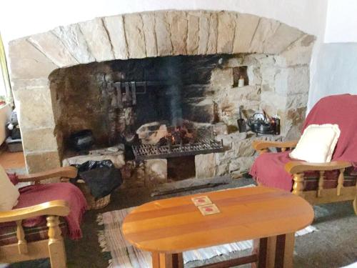sala de estar con chimenea de piedra con 2 sillas y mesa en Mask Cottage en Partry