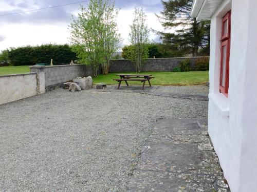 una mesa de picnic y un perro sentado al lado de un edificio en Mask Cottage, en Partry