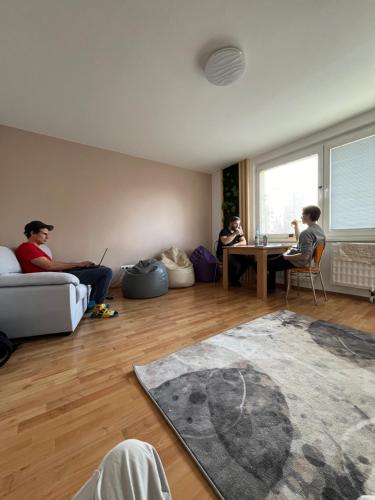 3 Personen sitzen in einem Wohnzimmer mit Laptops in der Unterkunft Bad Stuben Hostel in Turčianske Teplice