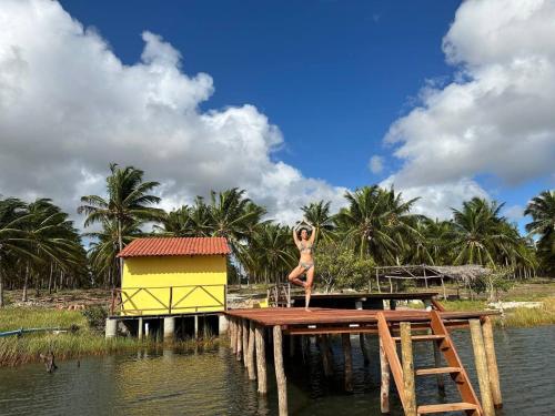 una mujer parada en un muelle en el agua en Glamping Bio-Dorf Cabana 1, en Trairi