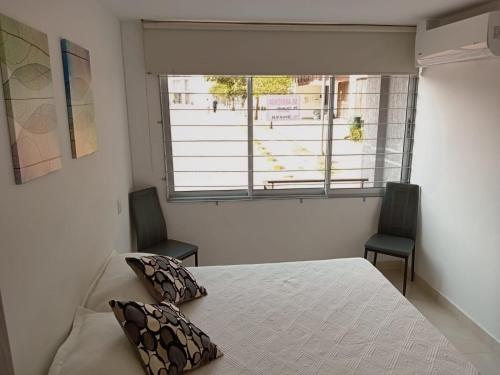 een slaapkamer met een bed met 2 stoelen en een raam bij Apto peña azul la aldea in Ricaurte