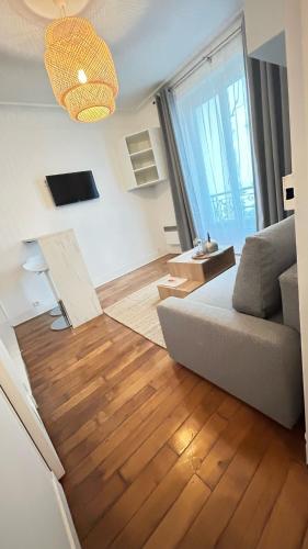 - un salon avec un canapé et du parquet dans l'établissement Coquet Studio Paris 14ème, à Paris