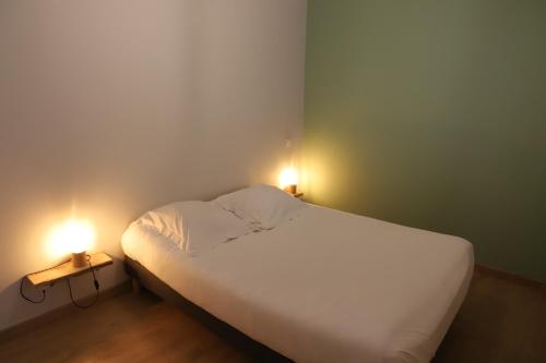 a bedroom with a white bed with two lights on it at Les oiseaux de la Slack in Ambleteuse
