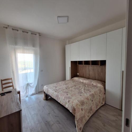a bedroom with a bed with white cabinets and a window at Casa vacanze Ricky in Porto Recanati