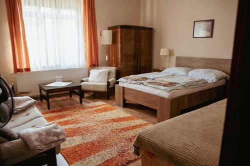een slaapkamer met een bed, een stoel en een bank bij Dobay Apartman Gyula in Gyula