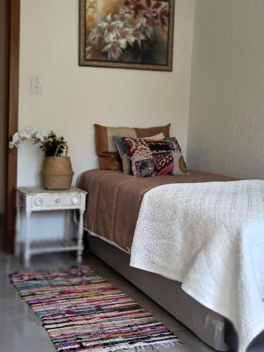 1 dormitorio con cama y mesa con alfombra en Recanto do bosque en Nova Petrópolis