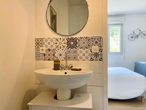 ein Bad mit einem Waschbecken, einem Spiegel und einem Bett in der Unterkunft Appartement proche Centre-ville in Saint Lo