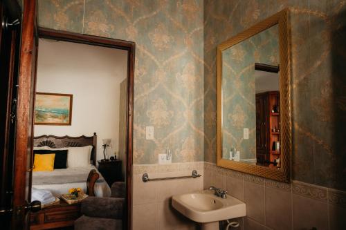 baño con lavabo, espejo y cama en Autumn in Antigua Boutique Hotel en Antigua Guatemala