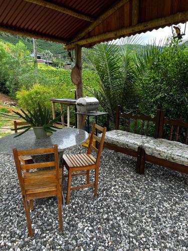a patio with two chairs and a table and a bench at Chalé de Madeira em Vargem Alta in Vargem Alta