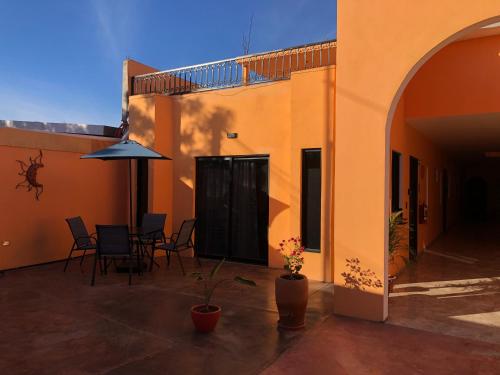 a patio with a table and chairs and an umbrella at Tres Iguanas Apart Hotel - New, cozy & spacious flats, short walk to beach in Loreto