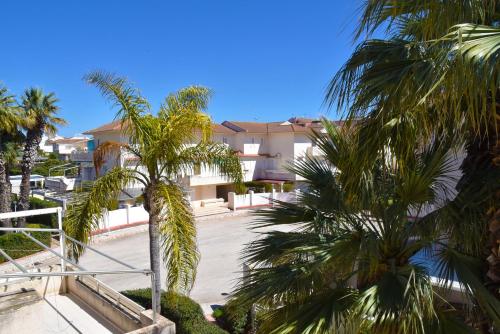 a building with palm trees in front of it at Punta di Mola House in Marina di Ragusa