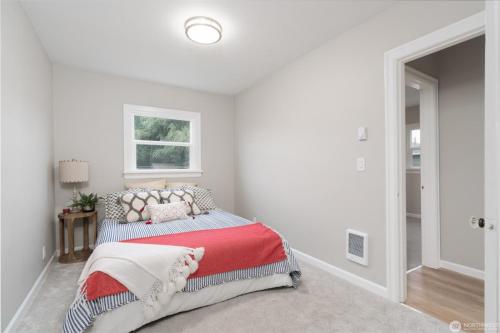ein weißes Schlafzimmer mit einem Bett mit einer roten Decke in der Unterkunft Cozy Sumner Home, Shops & Dining Nearby in Sumner