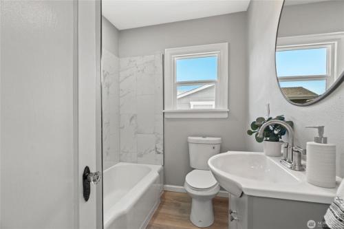 ein weißes Badezimmer mit einem Waschbecken, einem WC und einem Spiegel in der Unterkunft Cozy Sumner Home, Shops & Dining Nearby in Sumner