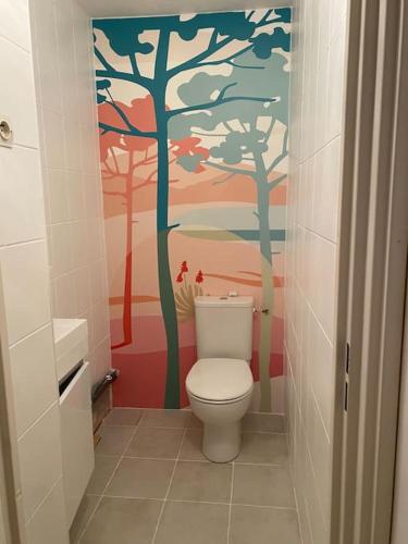 La salle de bains est pourvue de toilettes et d'une fresque murale représentant les arbres. dans l'établissement Maison familiale proche plages et Montpellier, à Mauguio