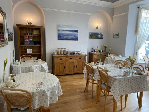 een eetkamer met 2 tafels met witte tafellakens bij Rivendell Guest House in Keswick