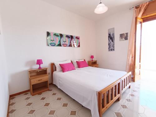 1 dormitorio con 1 cama blanca grande con almohadas rosas en Casa Relax a 200m dal mare, en Lido Marini
