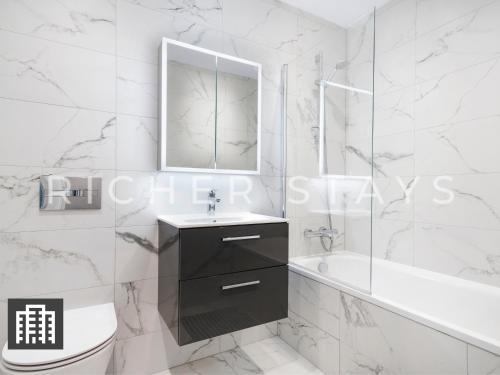 ein Badezimmer mit einem Waschbecken, einer Badewanne und einem Spiegel in der Unterkunft Cosy Studio Apartment- Hemel Hempstead High Street in Hemel Hempstead