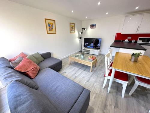 a living room with a blue couch and a table at Charming New 2BR Detached House-Central Headington- Wi-Fi, Netflix, Top Location in Oxford
