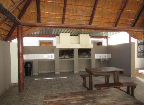 una habitación con una mesa y un banco en un edificio en BelaBela Guesthouse en Bela-Bela